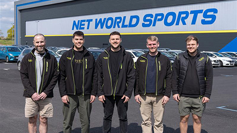 An image of five men posing in front of the Net World Sports Headquarters. 